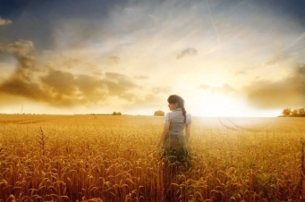 Яркая фотография девушки на золотистом пшеничном поле на фоне заката.